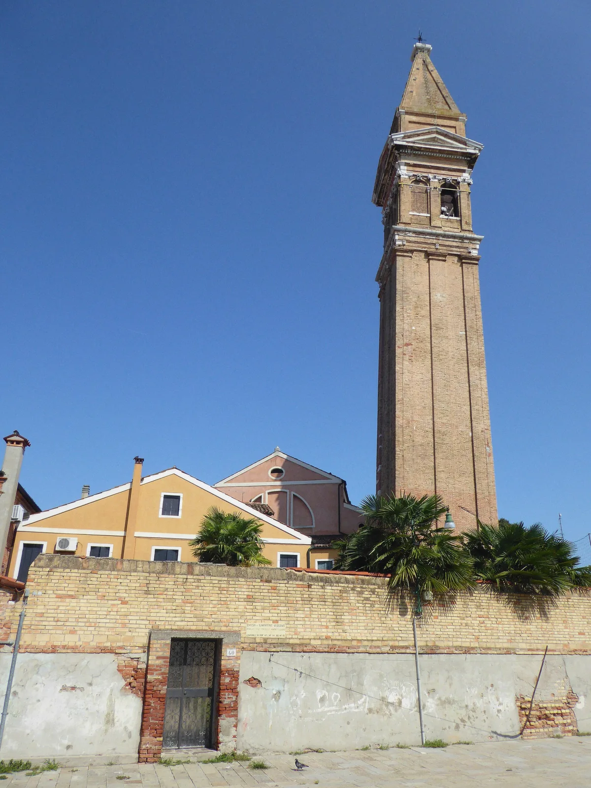 The leaning brick bell tower of Burano rising over pastel houses on the panoramic boat tour's island stop